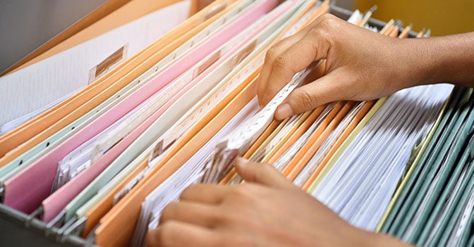 Hands sorting through filing cabinet